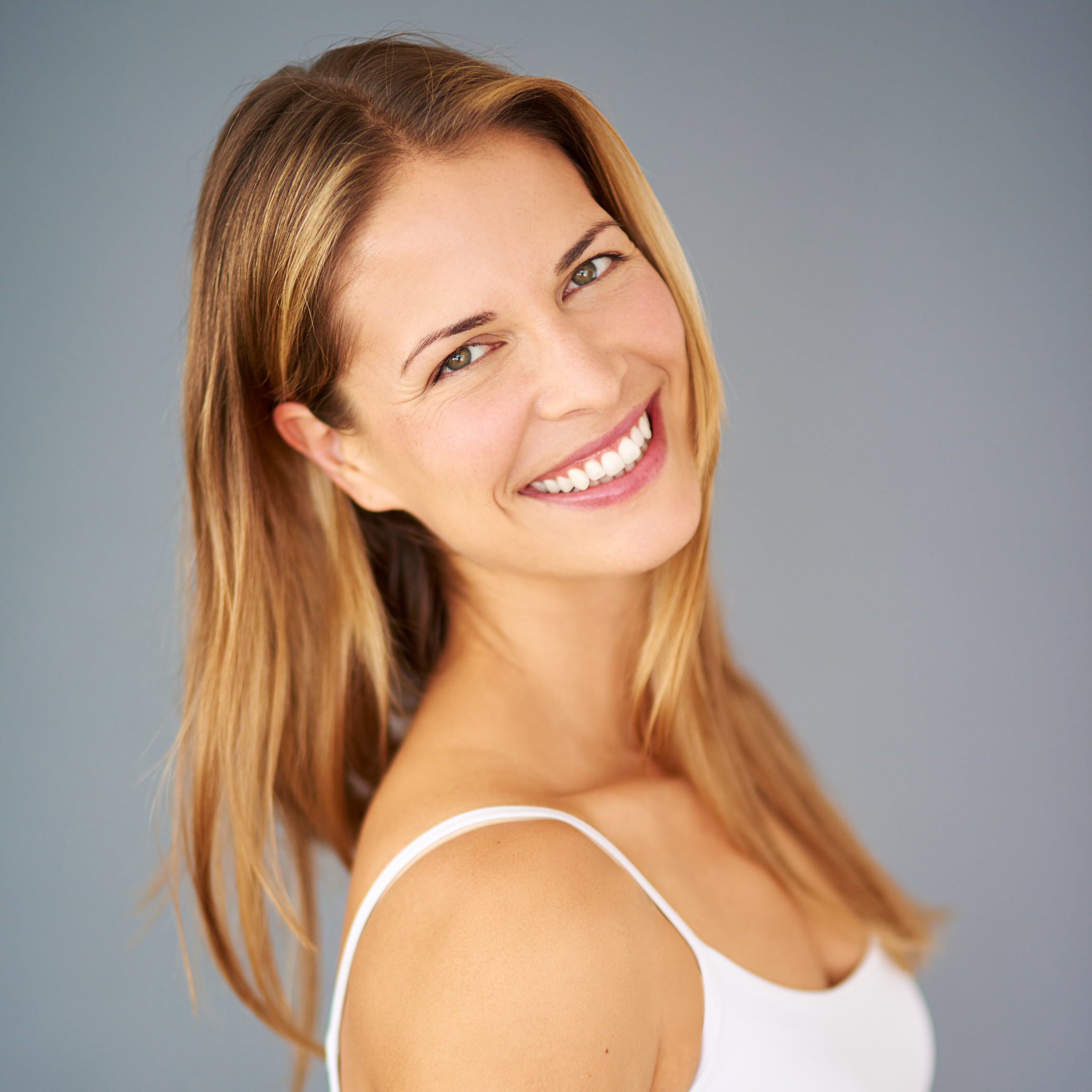 Studio shot of an attractive young woman posing against a gray background.
