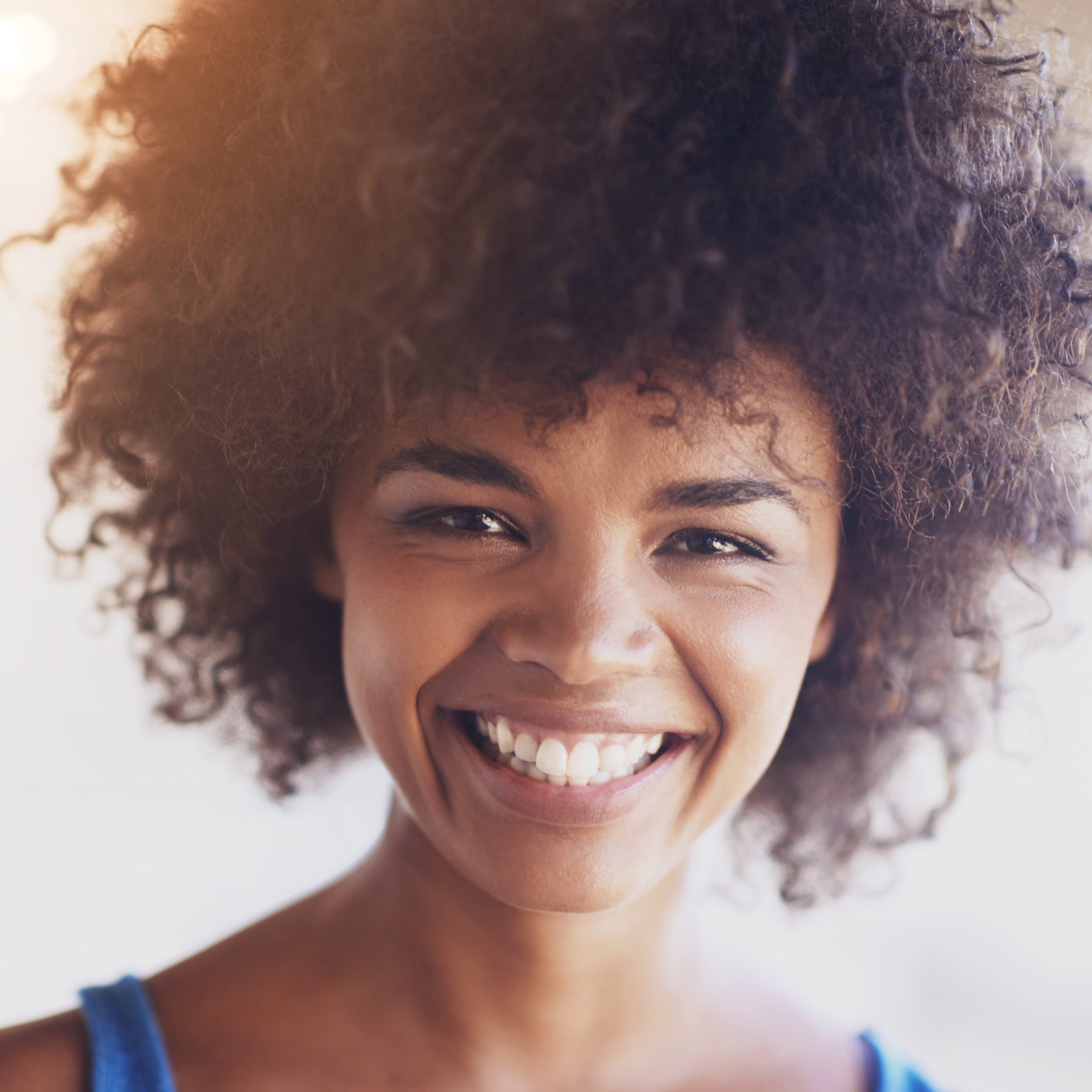 Woman, portrait and smile in fashion with closeup, natural beauty and casual outfit in summer. African person, face and happiness with afro hairstyle, wellness or trendy style with sunlight in Africa.